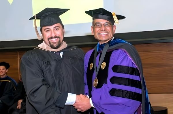 Larios and Professor M.P. Narayanan shake hands in cap and gown.