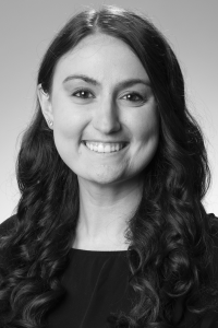 Photo of Michigan Ross Online MBA student Devon Leslie. The photo is in black and white but she has long dark curly hair and is wearing a dark shirt. She is smiling.