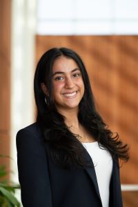 Photo of Michigan Ross BBA student Nadine Fayad. She has long dark hair and is wearing a black jacket with a white shirt underneath. She is looking at the camera and smiling.
