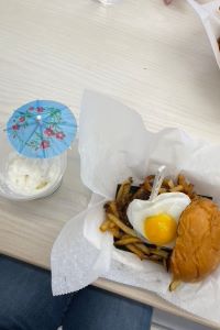 Photo of Frita Batidos burger with an egg on top and a fruit batido with a decorative umbrella