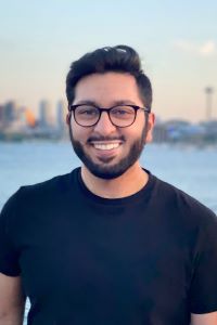 Photo of Jamil Rehemtulla Michigan Ross Online MBA student with short dark hair and glasses and beard wearing a black short sleeve shirt