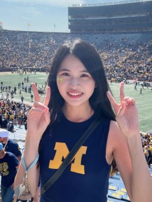 Jie Shen smiling in the Big House during a football game.