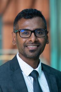 Photo of Michigan Ross Weekend MBA student Kishor Mahajan. He is wearing a blue suit with a white shirt. He is wearing glasses and is smiling. 