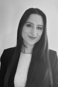 Photo of Michigan Ross Online MBA student Marisa Maite. The photo is in black and white but she has long dark hair and is wearing a dark colored jacket with a light colored shirt underneath. She is smiling. 