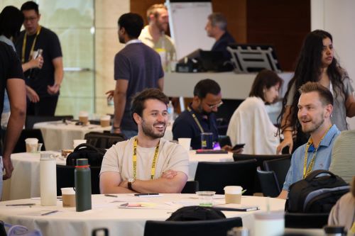 Students smiling and talking at a table with a white tablecloth in a large room.