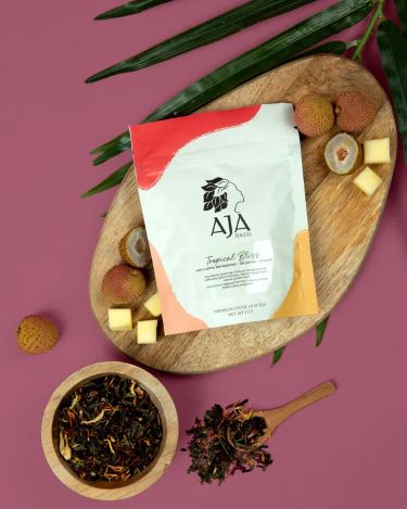 A bag of loose leaf tea displayed on a wood cutting board alongside cheese and fruit