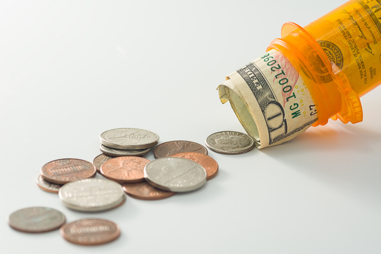 Money spilling out of prescription pill bottle