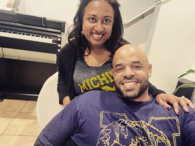 A couple smiling in front of a piano