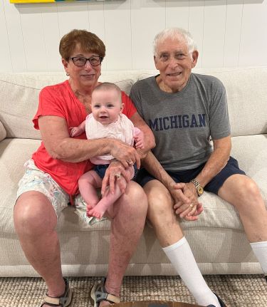 A couple holding their grandchild on a couch