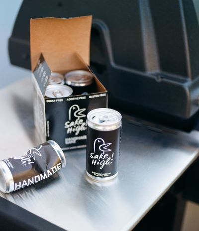 Cans of Sake High sit on the shelf of an outdoor grill