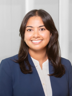 A woman with dark brown hair wearing a blue suit and white shirt