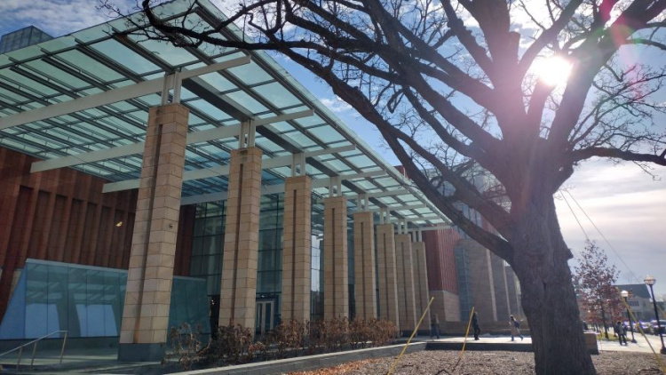 Photo of the outside of the Ross School of Business building. The sun is shining brightly and there is a tree out front that doesn't have any leaves. 