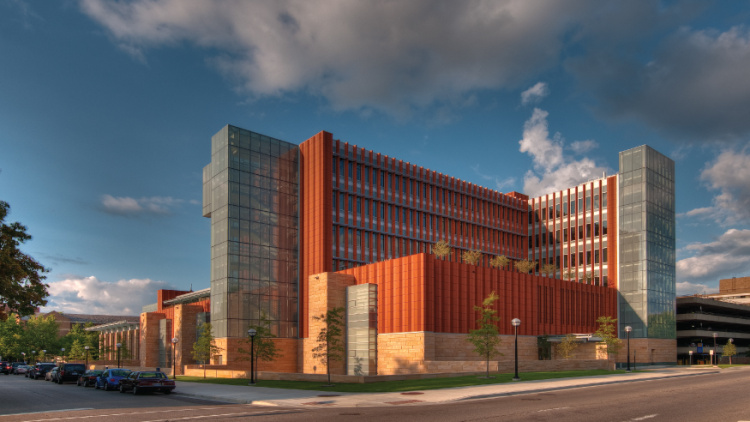 Modern academic building with glass and brick exterior under a partly cloudy sky.