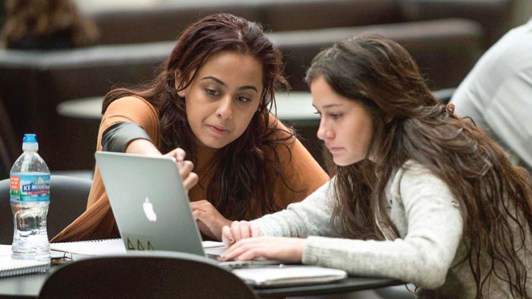 Two people collaborating at a laptop, focused on the screen.