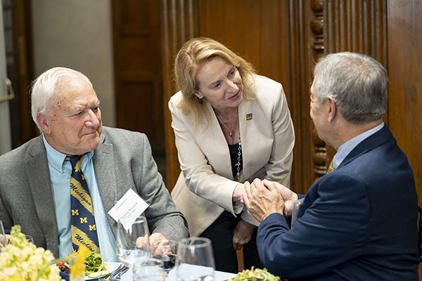 Dean Matusik greets two people sitting at a table