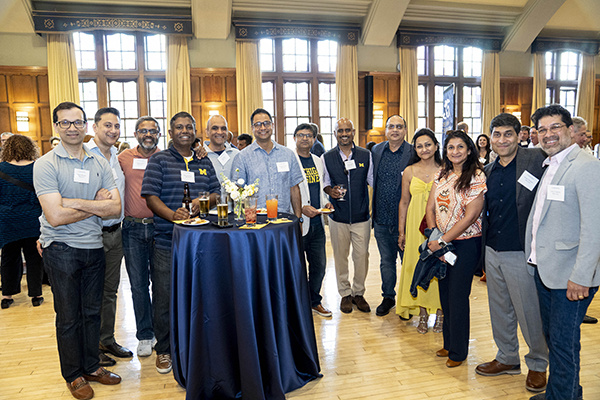 large group of people pose around smaller table in a ballroom