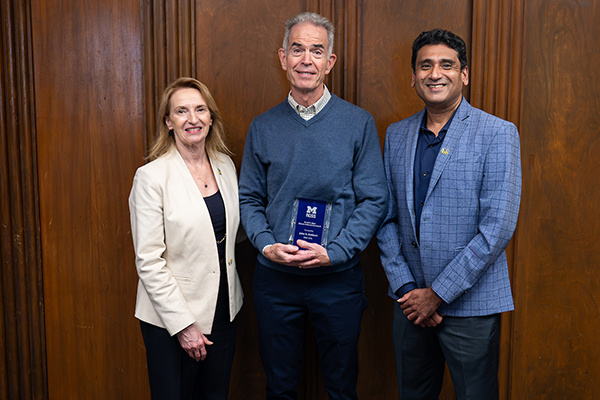 3 people posing with award. One of them is Dean Matusik