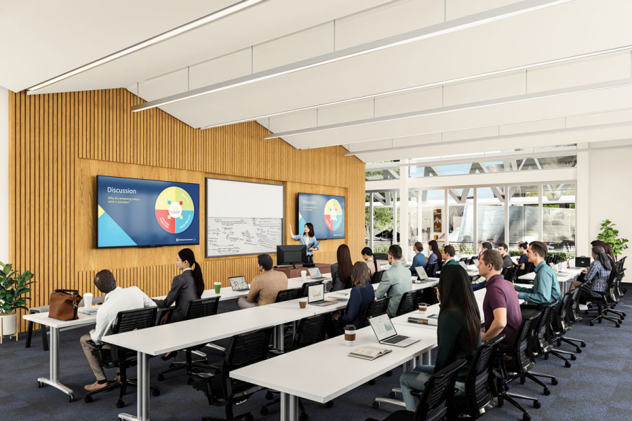 Students in a modern classroom listen to a presentation with slides displayed on large screens.