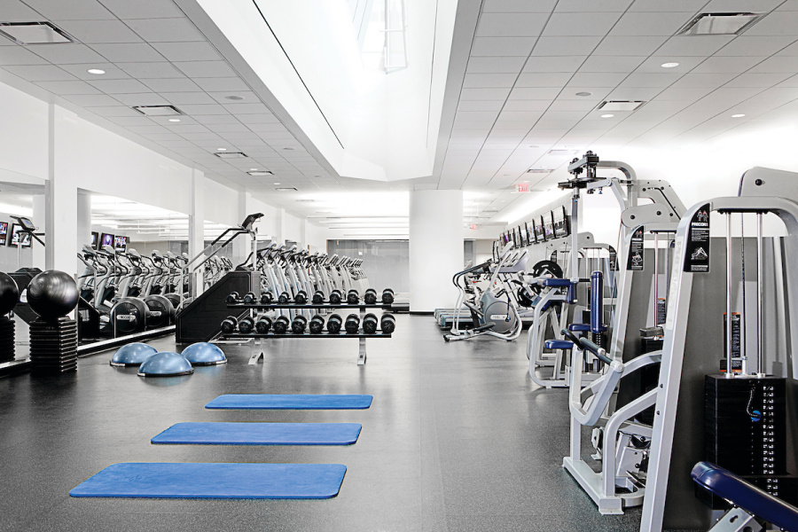 Spacious gym with free weights, exercise machines, and three blue mats on the floor.