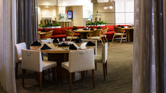 Modern restaurant dining area with neatly set tables and red booth seating.