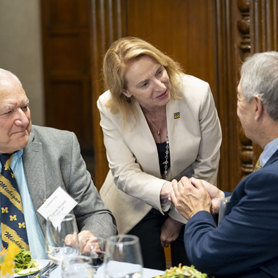 Dean Matusik greets two people sitting at a table