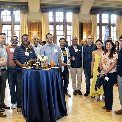 large group of people pose around smaller table in a ballroom