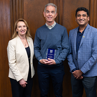 3 people posing with award. One of them is Dean Matusik