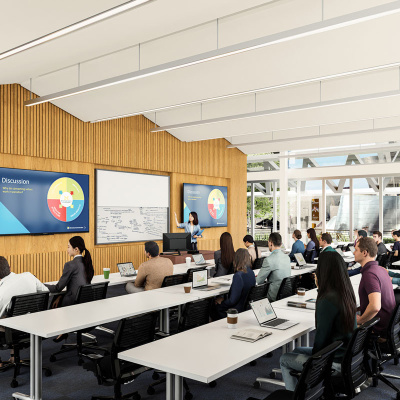 Students in a modern classroom listen to a presentation with slides displayed on large screens.
