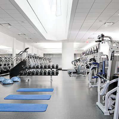 Spacious gym with free weights, exercise machines, and three blue mats on the floor.