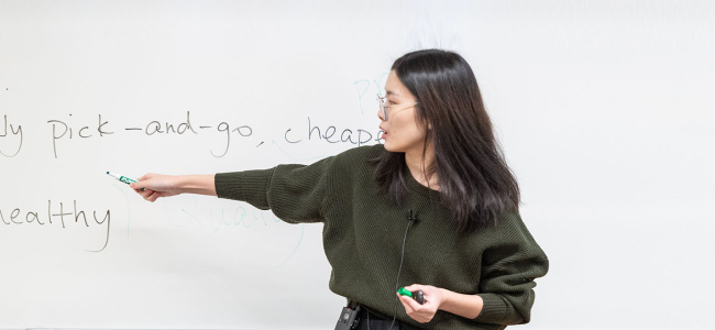 PhD student teaching class at whiteboard