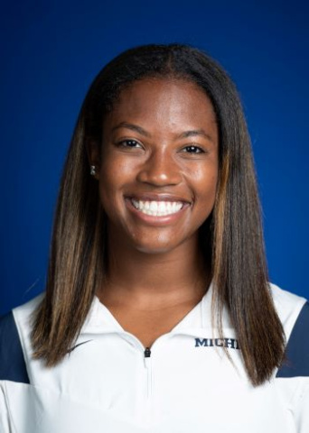 A woman in a Michigan Ross jacket smiles for a professional headshot