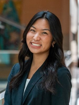 Person smiling in a professional setting with a blurred background.