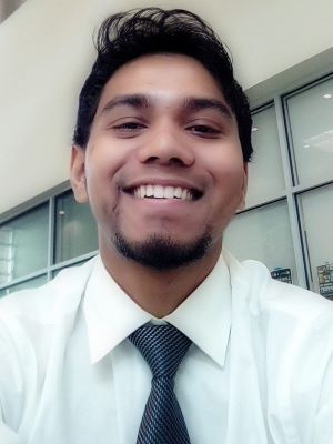 Smiling person wearing a white shirt and tie in an indoor setting.