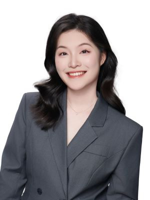 Person smiling in a gray blazer against a white background.