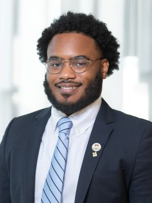 Man in a suit and tie smiling in a bright, professional setting.