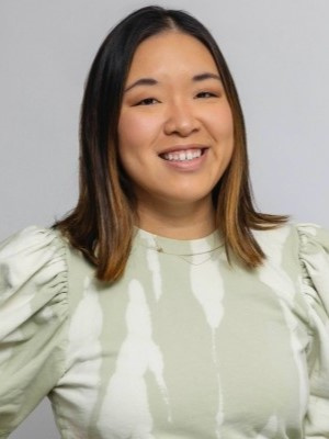 Person smiling in a light green patterned shirt against a plain background.