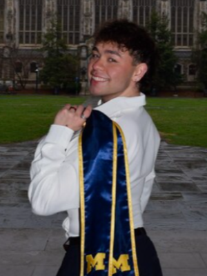 Person smiling with a University of Michigan graduation stole draped over their shoulder.