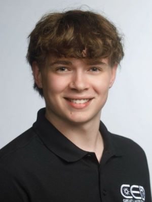 Smiling young person wearing a black collared shirt with a white embroidered logo.