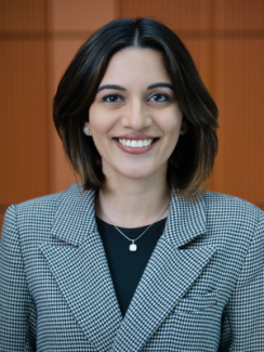 Woman smiling in a professional headshot wearing a checkered blazer and necklace.