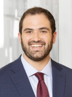 Man in a blue suit and red tie smiling in an office setting.