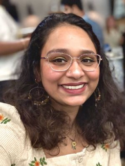 Person smiling at the camera in a busy indoor setting.