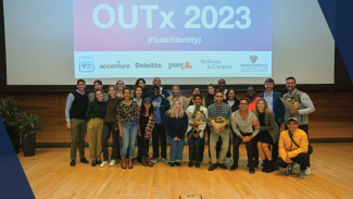 A group of students taking a photo on stage at the OUTx event