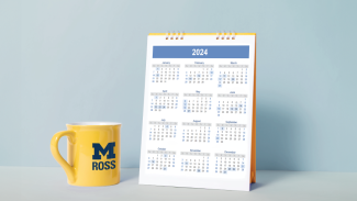 Photo of a calendar and a yellow Michigan Ross coffee mug