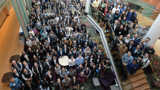 A huge crowd of hundreds of students in the Winter Garden looking up at the camera for a large group photo from above
