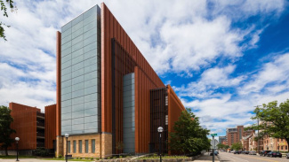 Photo of exterior of the Ross School of Business on a sunny day with blue sky and white clouds