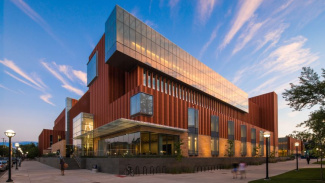 Photo of the exterior of the Ross School of Business building with a blue sky and clouds. 