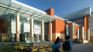 The exterior of the Ross building at sunset or sunrise with two students walking around in the foreground