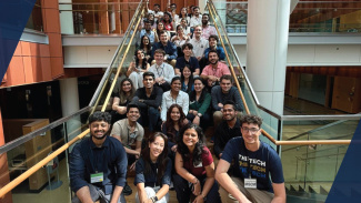 A large group of students posing on the stairs in the Ross building, smiling