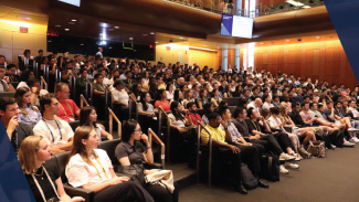 A large crowd of students sits in the auditorium at Orientation.