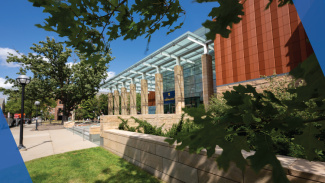 The front of the Ross building, with a blue sky in the background and leaves of a tree in the foreground of the image